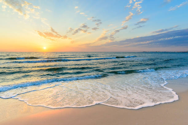Long wave on the coast, dawn on the sea, Tunisia large foam waves in the sand, diagonal clouds, yellow light of dawn in the blue sky